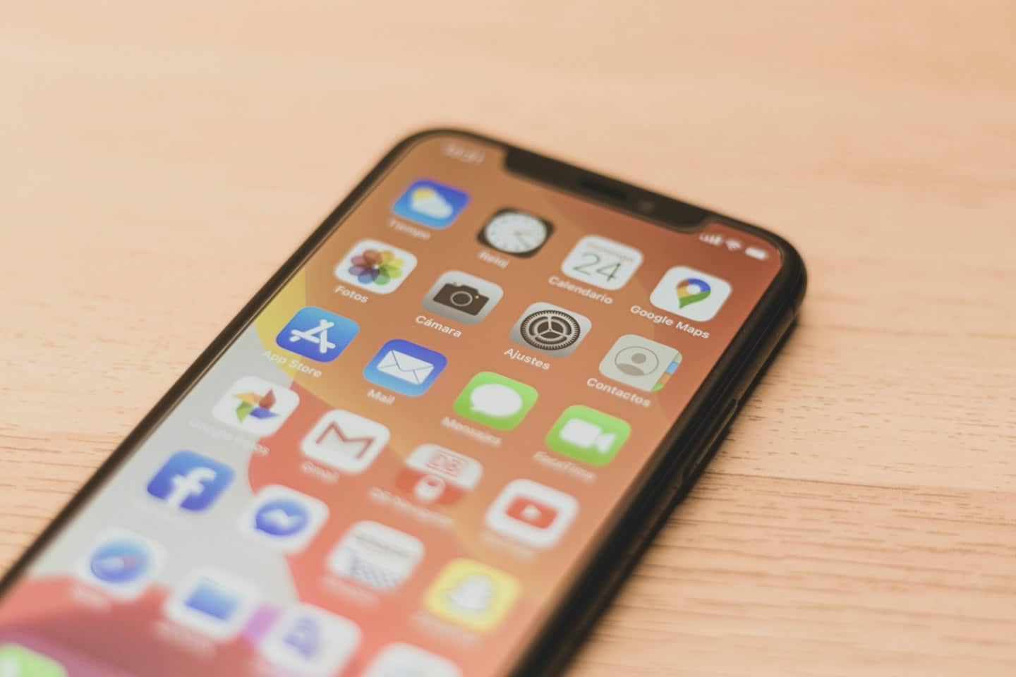 Smartphone with app icons displayed on a wooden table.